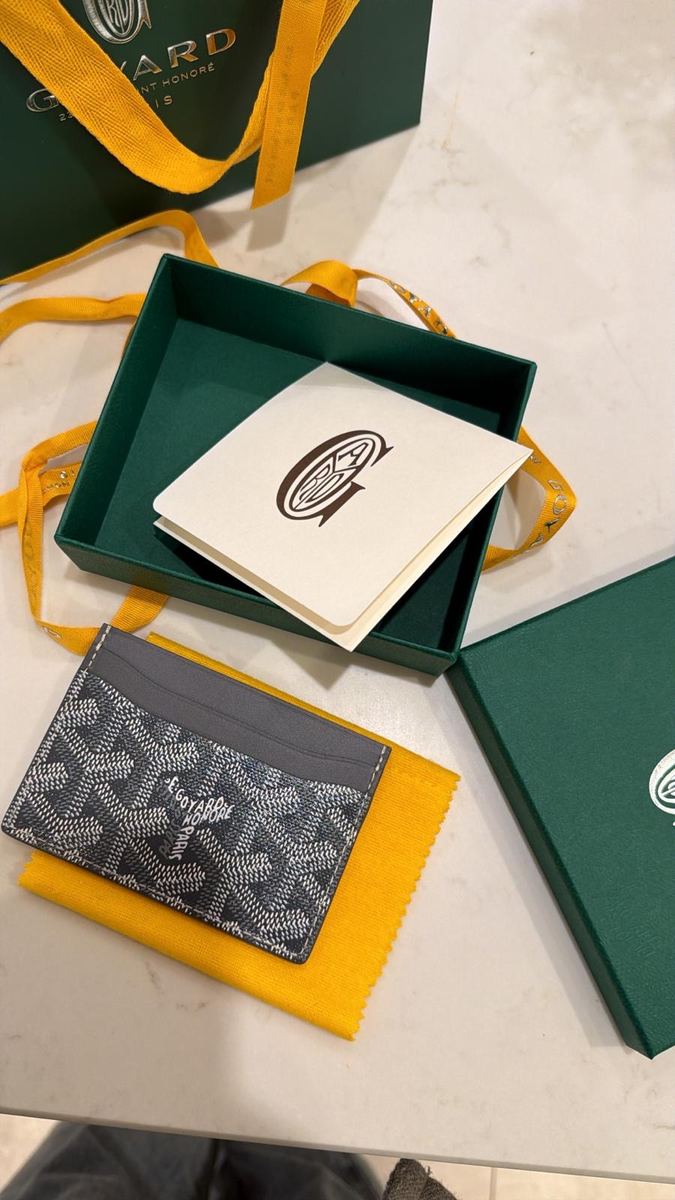 A grey Goyard card holder with its green box