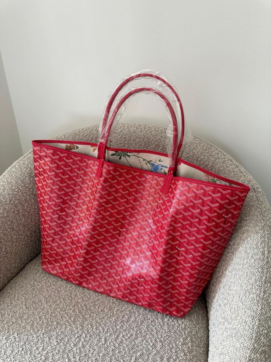 A red Goyard tote on an armchair