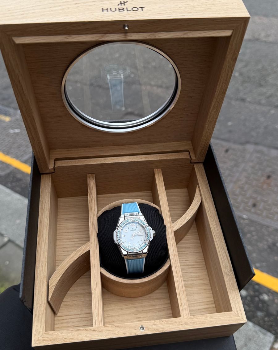 A Hublot watch with a blue strap in its wooden presentation box