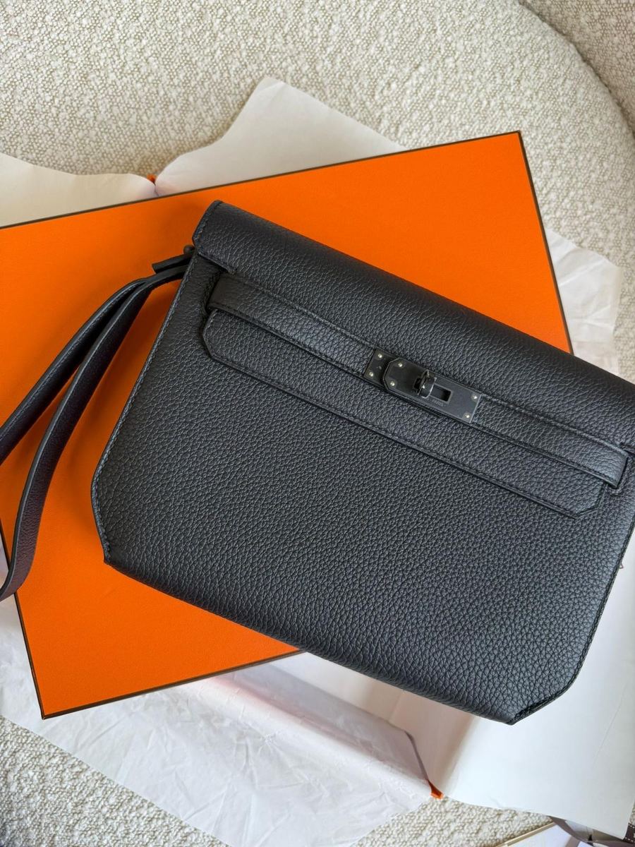A black Hermès Kelly pouch on an orange box