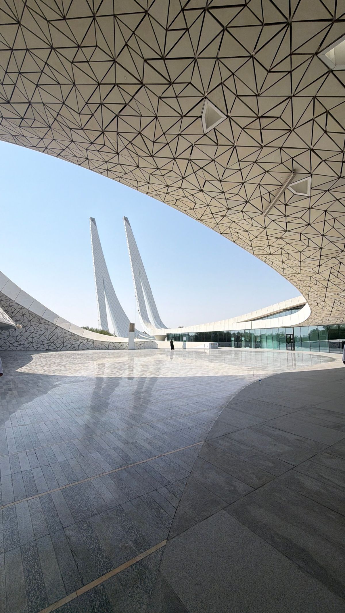 White geometric canopy and twin minarets against a clear sky