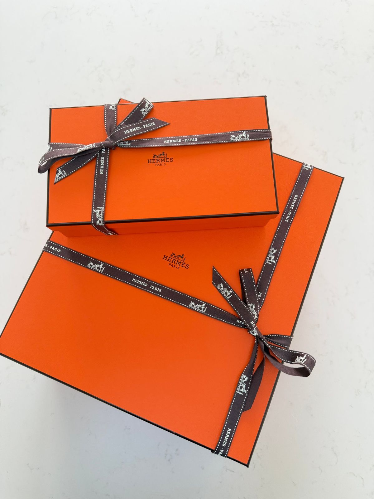 Two orange Hermès boxes tied with brown ribbon