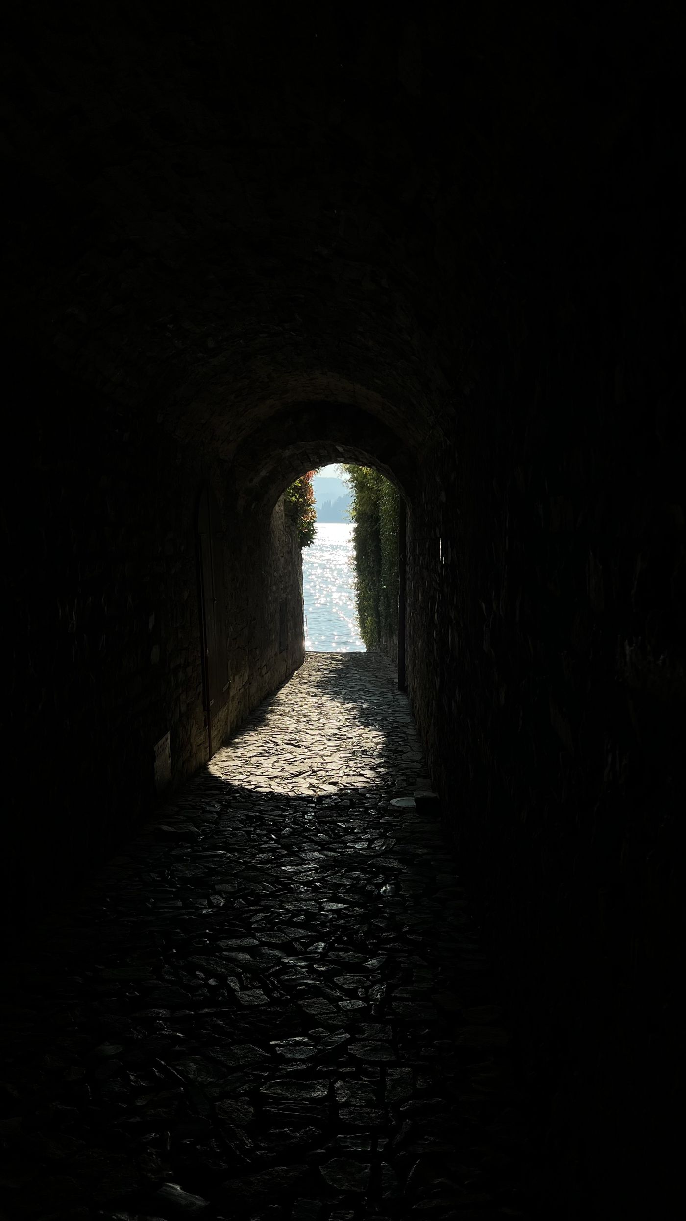 A dark stone passage opening onto sunlit water