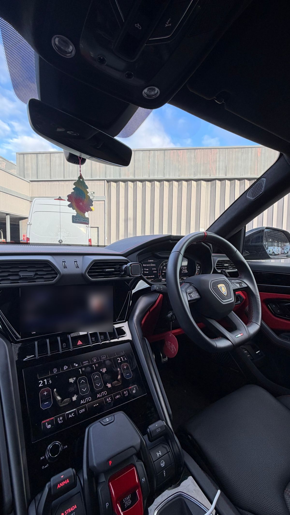 The driver's seat and dashboard of a Lamborghini Urus with red trim